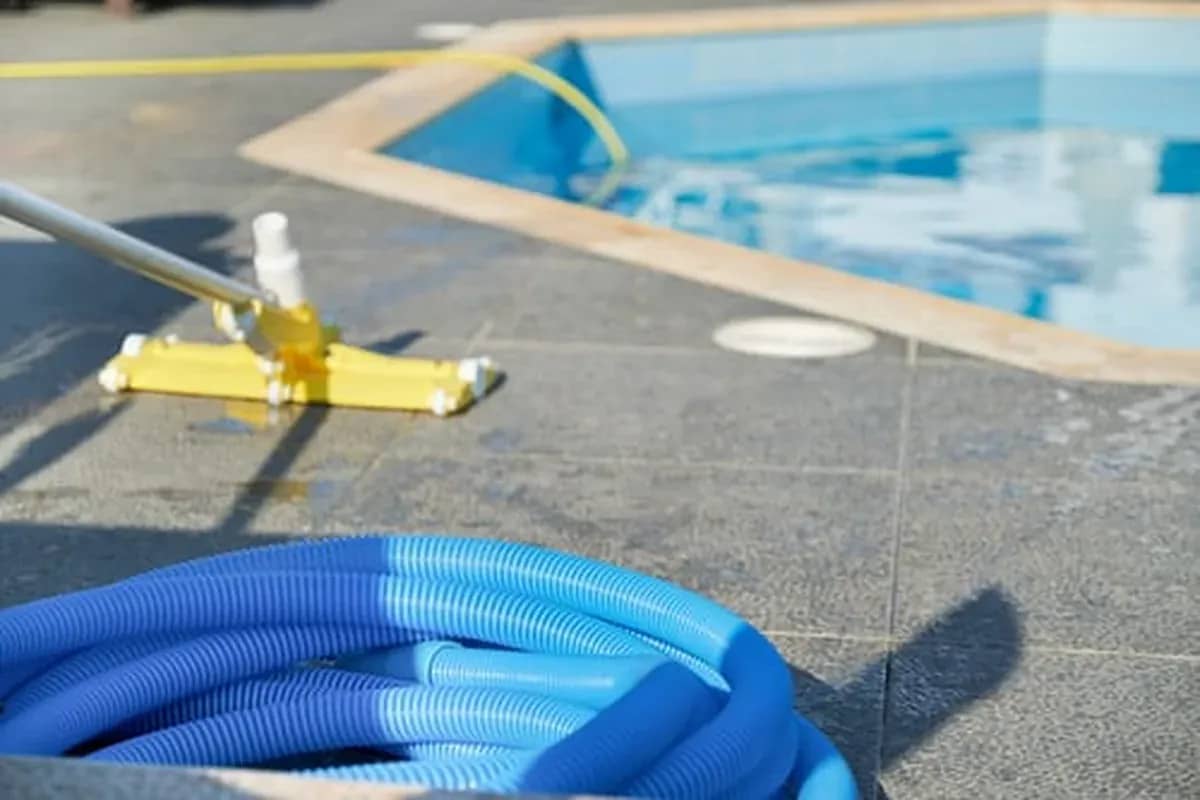 Pool cleaning equipment and hose at the edge of a swimming pool